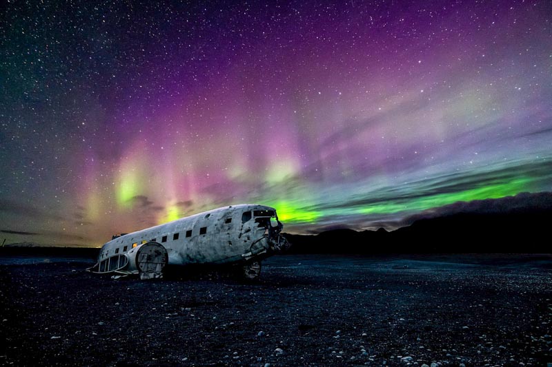 come fotografare l'aurora boreale: un aereo abbandonato in una spiaggia sotto l'aurora boreale