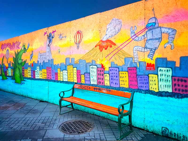 una panchina colorata sotto un murales di cartoni animati
